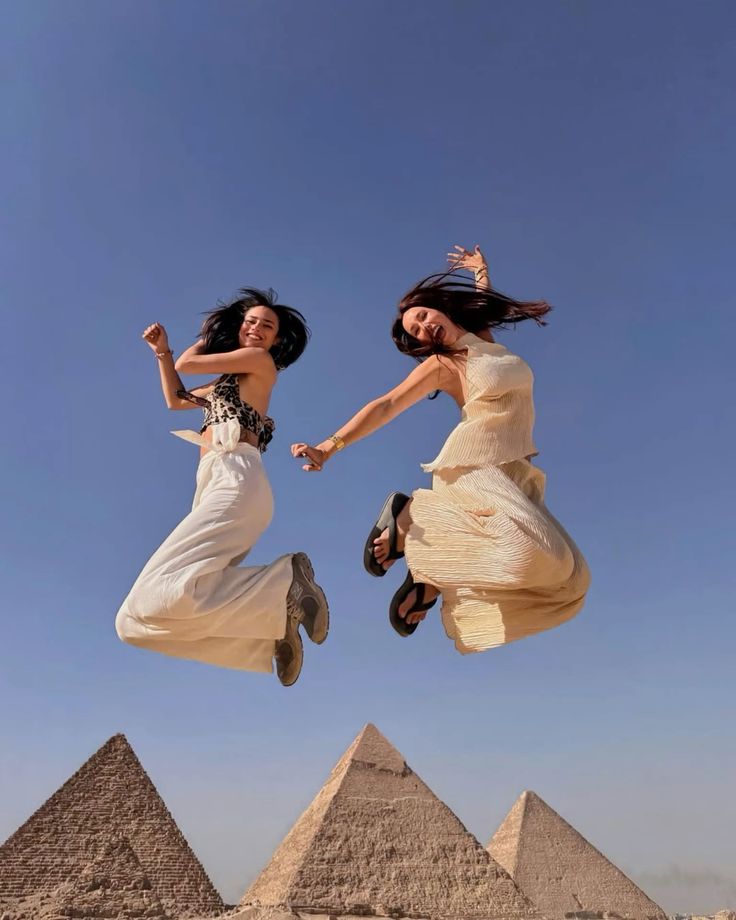 The three Pyramids of Giza glowing at sunrise with a small tour group